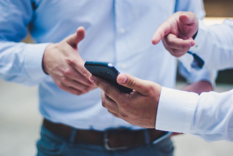 men pointing at a phone